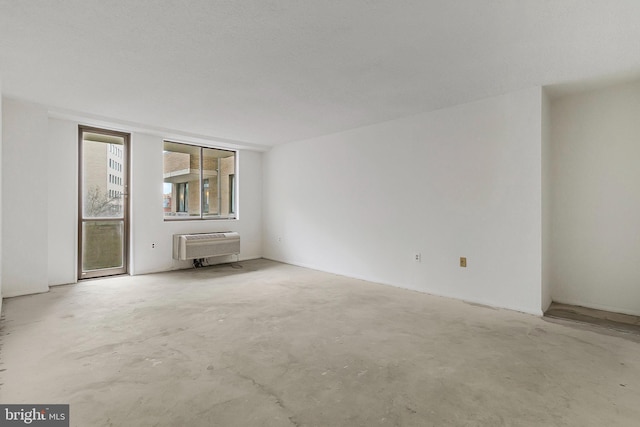 unfurnished room with unfinished concrete floors and a wall mounted air conditioner