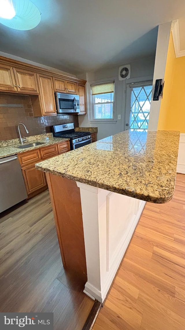 5716 Willowton Ave, Baltimore, MD 21239 - kitchen with light wood-style flooring, brown cabinets, appliances with stainless steel finishes, and a sink