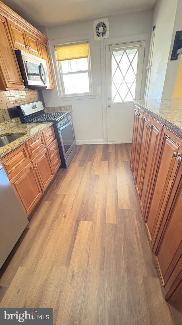 5716 Willowton Ave, Baltimore, MD 21239 - kitchen with stainless steel appliances, light wood-style floors, visible vents, and light stone counters