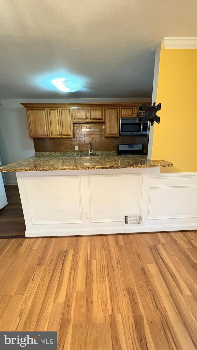 5716 Willowton Ave, Baltimore, MD 21239 - kitchen featuring tasteful backsplash, visible vents, dark stone countertops, appliances with stainless steel finishes, and light wood finished floors
