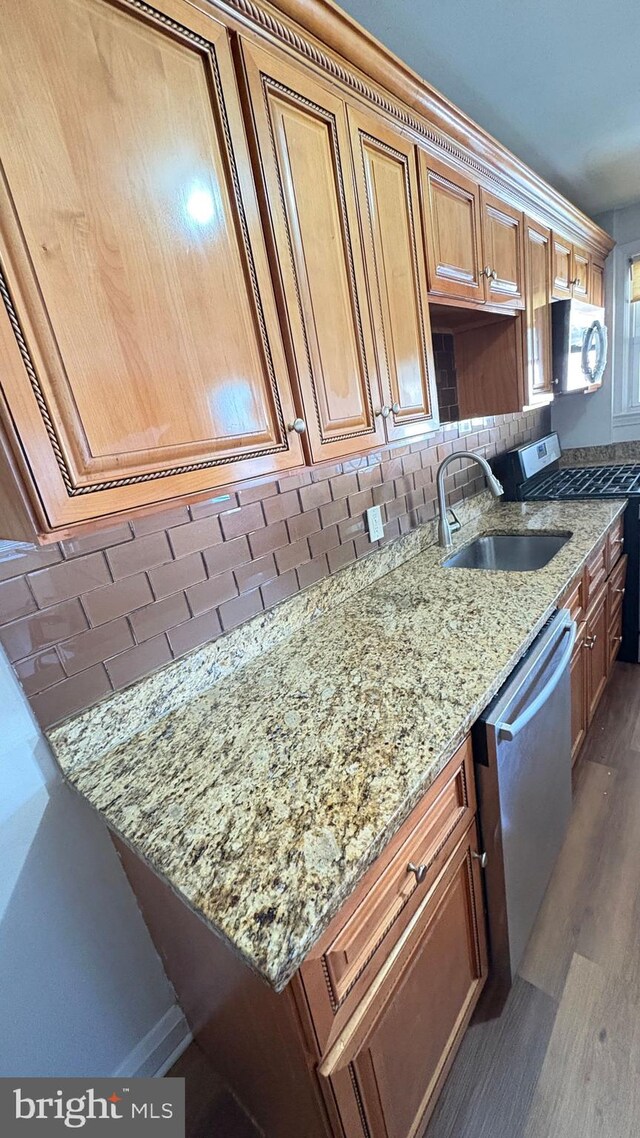 5716 Willowton Ave, Baltimore, MD 21239 - kitchen with appliances with stainless steel finishes, light stone countertops, dark wood-type flooring, decorative backsplash, and a sink