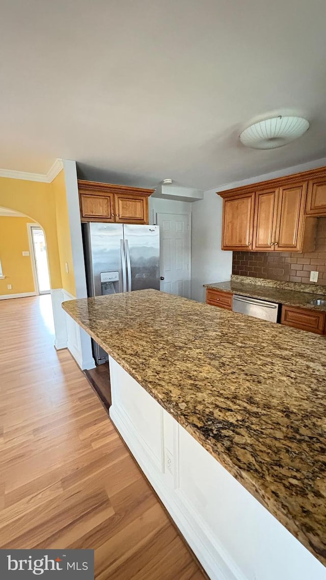 5716 Willowton Ave, Baltimore, MD 21239 - kitchen featuring backsplash, crown molding, light wood-style floors, stainless steel appliances, and arched walkways