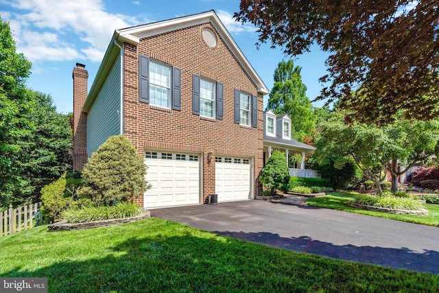 view of front of home with a lawn, brick siding, driveway, and a chimney