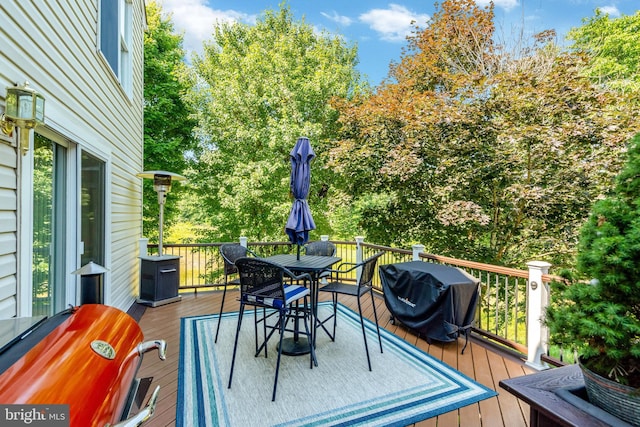 wooden terrace featuring outdoor dining space and a grill