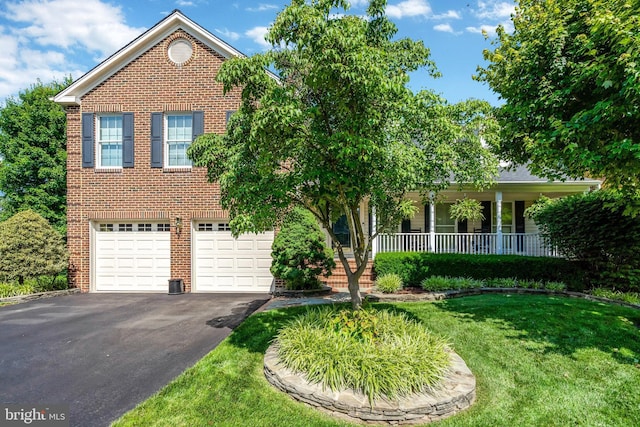 view of front of house with covered porch, a garage, brick siding, driveway, and a front lawn