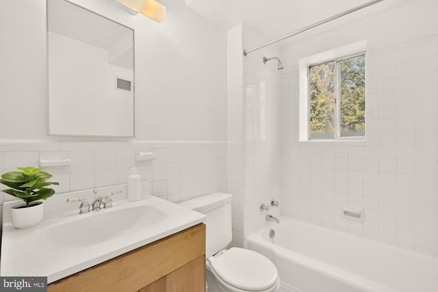 full bath with visible vents, bathing tub / shower combination, toilet, vanity, and tile walls