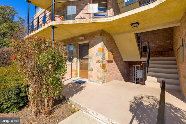 entrance to property featuring brick siding and a balcony