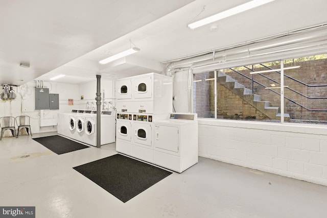 shared laundry area with separate washer and dryer, concrete block wall, stacked washer and clothes dryer, and electric panel