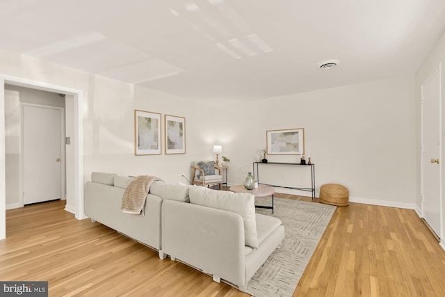 living room featuring light wood-style floors, visible vents, and baseboards