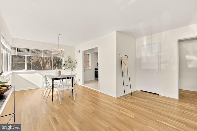 dining room with light wood-style flooring, a chandelier, and baseboards