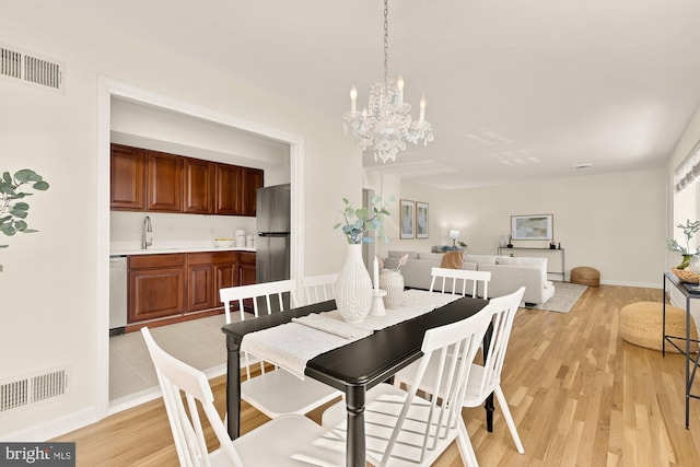 dining room with light wood-type flooring, visible vents, and baseboards