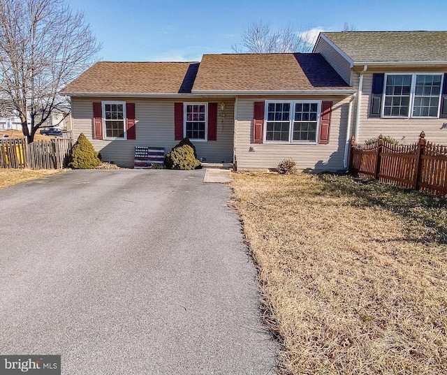 view of front of house with roof with shingles, fence, and driveway