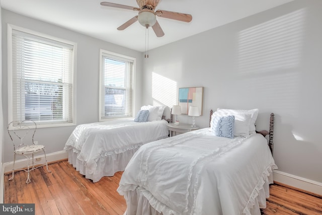 bedroom with ceiling fan, wood finished floors, and baseboards