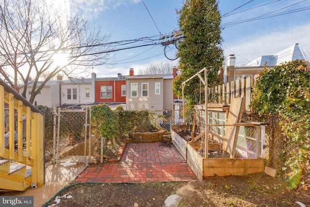 rear view of property featuring a vegetable garden, fence, and a patio