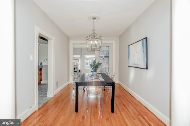 dining room with baseboards, visible vents, a chandelier, and wood finished floors