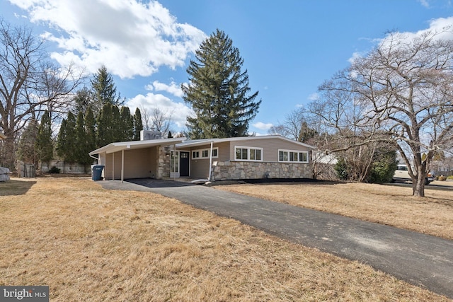 view of front of property featuring aphalt driveway, a front yard, stone siding, and an attached carport