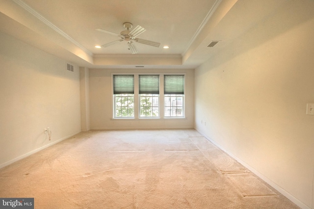 spare room with ornamental molding, a tray ceiling, visible vents, and light carpet