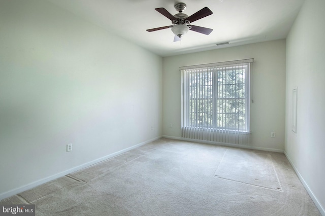 spare room featuring light carpet, ceiling fan, visible vents, and baseboards