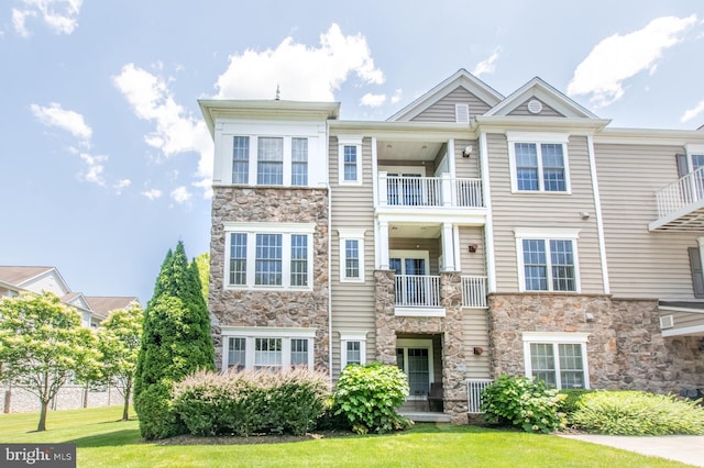 multi unit property featuring stone siding and a front lawn