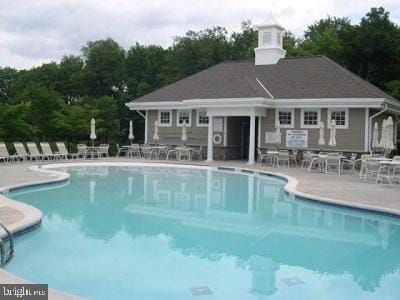 community pool with an outbuilding and a patio area