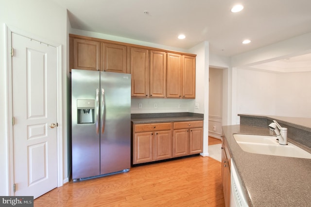 kitchen featuring dark countertops, light wood-style flooring, stainless steel refrigerator with ice dispenser, a sink, and recessed lighting