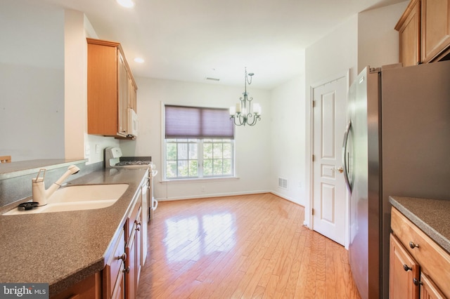 kitchen with pendant lighting, dark countertops, white appliances, and a sink