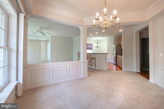 empty room with crown molding, a decorative wall, wainscoting, light carpet, and ceiling fan with notable chandelier