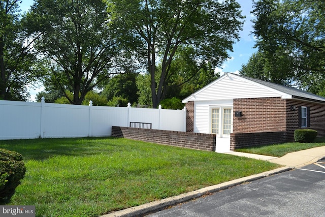 view of property exterior with a yard, brick siding, and fence