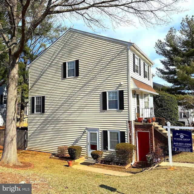 view of side of home with a lawn and fence