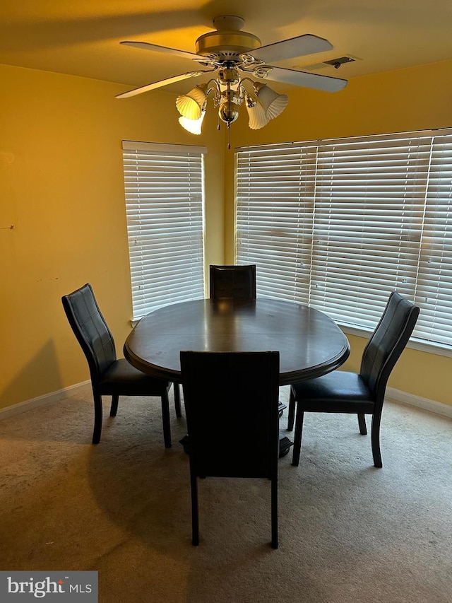 carpeted dining space featuring visible vents, a ceiling fan, and baseboards