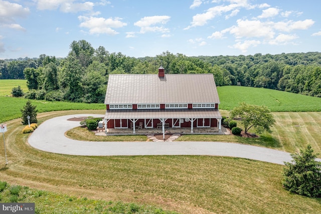 view of front facade with a front yard, metal roof, a rural view, and curved driveway