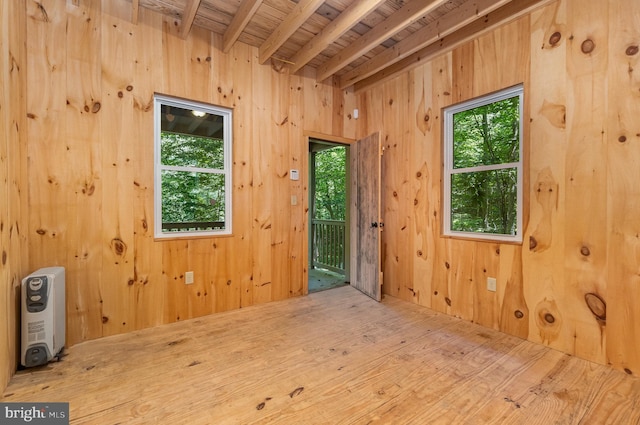 spare room with wood ceiling, hardwood / wood-style flooring, beam ceiling, and wooden walls