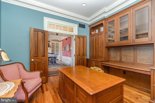 home office featuring light wood-style flooring, visible vents, and crown molding