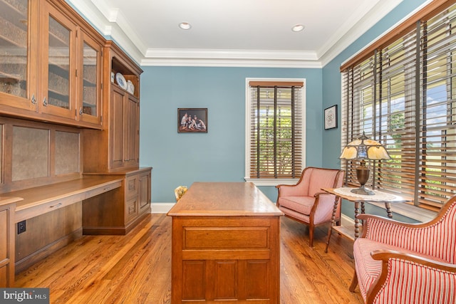 office space with baseboards, ornamental molding, built in study area, and light wood-style floors