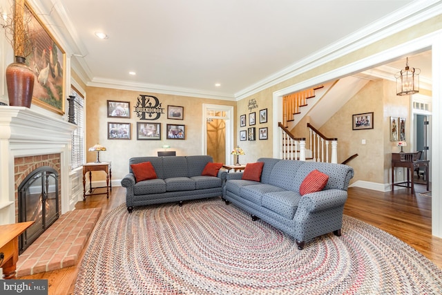 living room with baseboards, ornamental molding, wood finished floors, stairs, and a fireplace