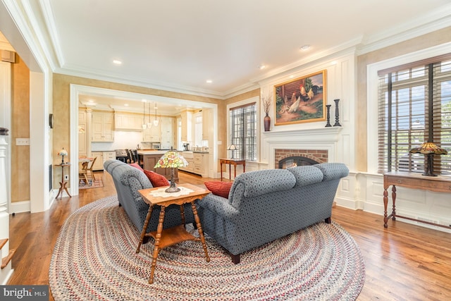 living area featuring light wood-style floors, a brick fireplace, and crown molding