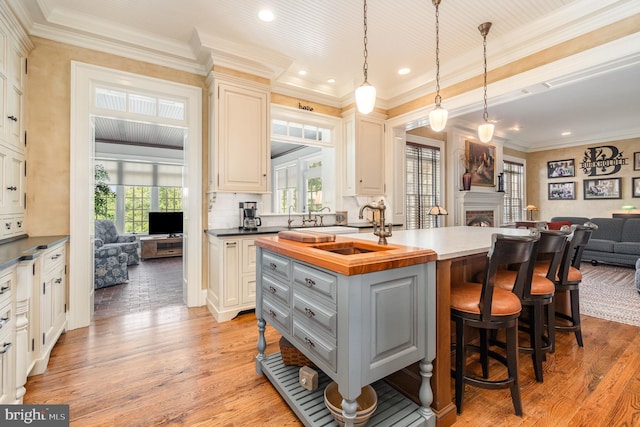 kitchen with open floor plan, hanging light fixtures, gray cabinets, a kitchen bar, and a center island with sink