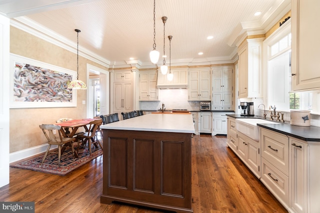 kitchen with dark countertops, a kitchen island, pendant lighting, and a sink