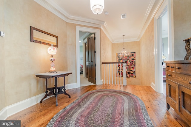 corridor featuring a notable chandelier, visible vents, baseboards, light wood finished floors, and crown molding