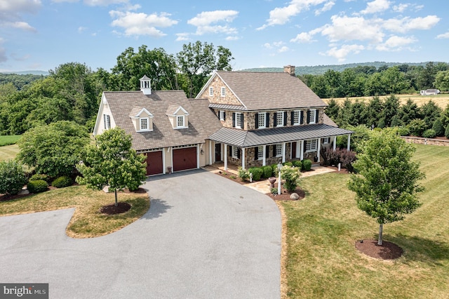 shingle-style home featuring a standing seam roof, aphalt driveway, a porch, and a front yard