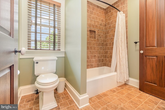 bathroom featuring baseboards, toilet, and shower / bathtub combination with curtain