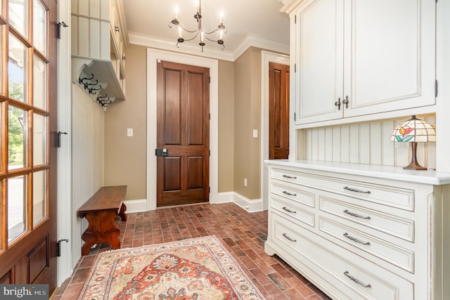 mudroom featuring brick floor, a notable chandelier, crown molding, and baseboards