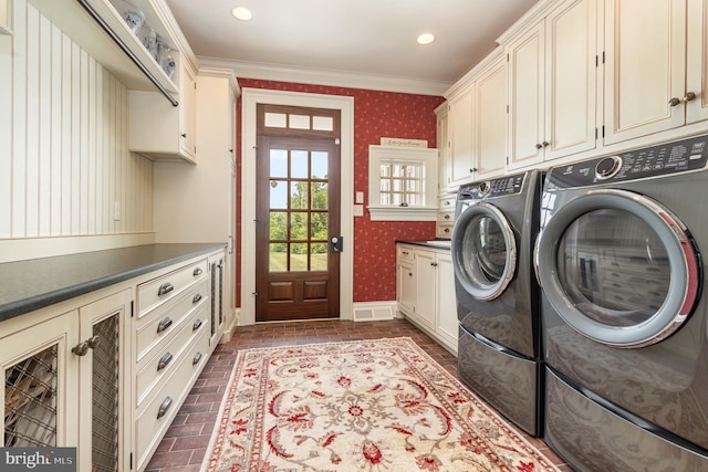 laundry room featuring washer and clothes dryer, brick floor, cabinet space, and wallpapered walls