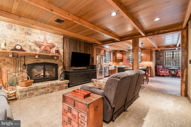 living area with a fireplace, light colored carpet, visible vents, wood ceiling, and beamed ceiling