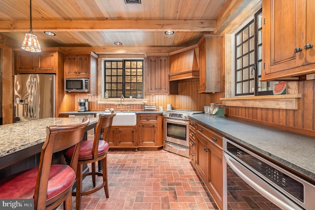 kitchen with stainless steel appliances, hanging light fixtures, brown cabinets, and custom range hood