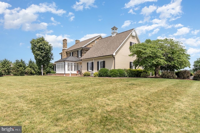 view of side of home featuring a chimney and a yard