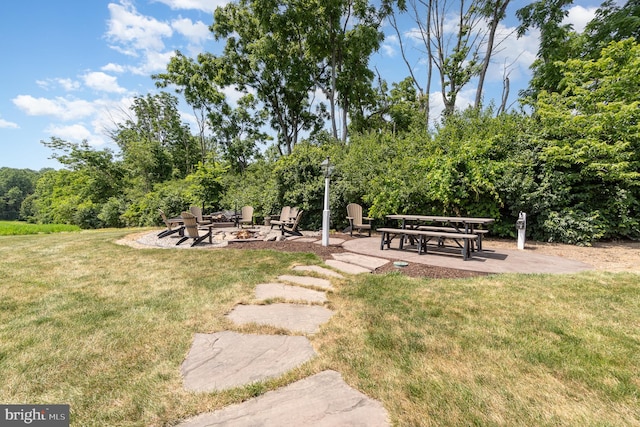 view of property's community featuring a patio area, a fire pit, and a yard