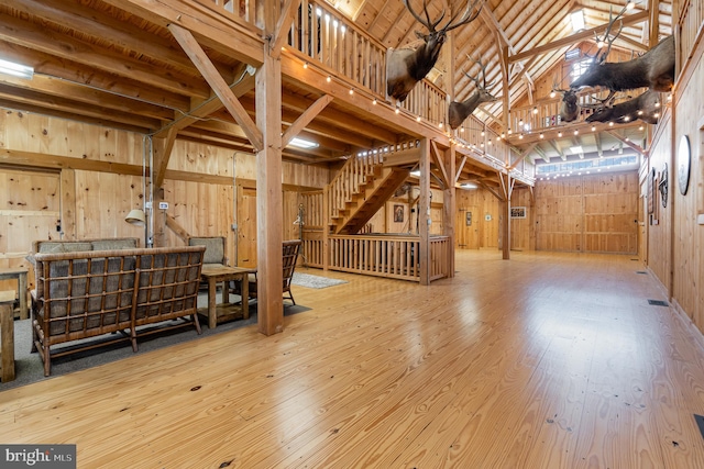 interior space with high vaulted ceiling, wood walls, and light wood finished floors