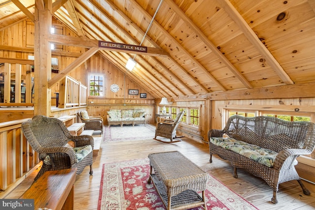 sitting room with vaulted ceiling with beams, light wood-style floors, wood ceiling, and wood walls