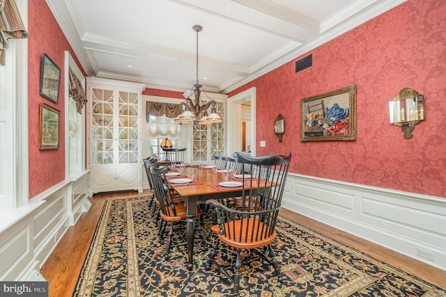 dining area featuring crown molding, wainscoting, wood finished floors, beamed ceiling, and wallpapered walls